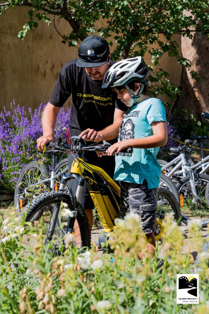 Adult teaching child to ride a bicycle outdoors.