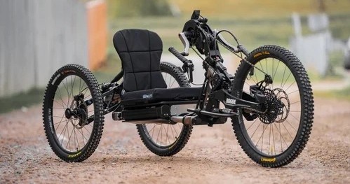 Four-wheeled off-road adaptive bike with thick tires on a gravel path.
