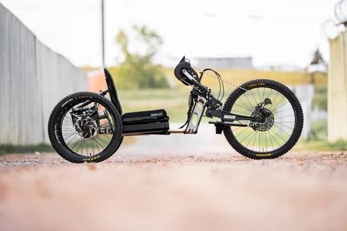 A recumbent trike with thick tires on a dirt path, viewed from the side.